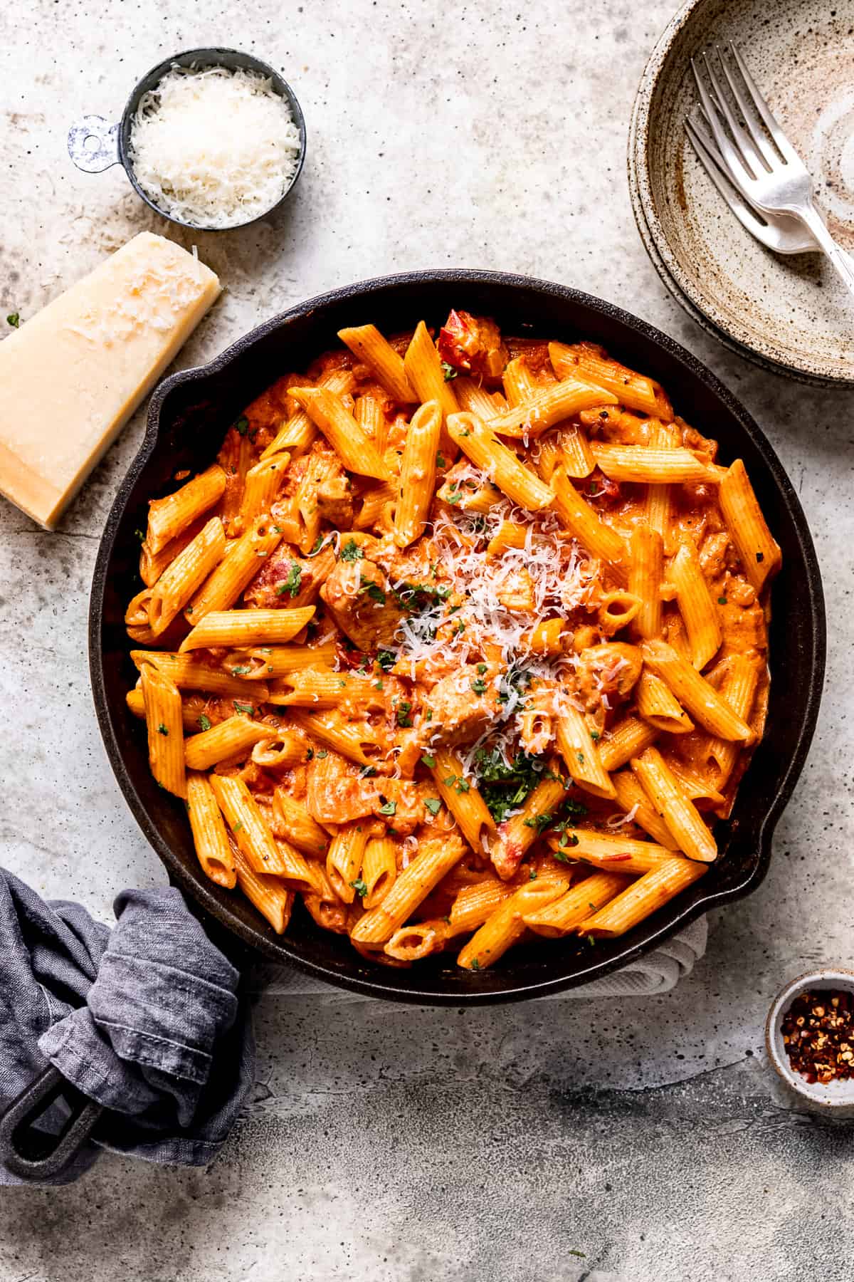 Cajun chicken pasta on a table with parmesan cheese.