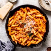 Cajun chicken pasta on a table with parmesan cheese.