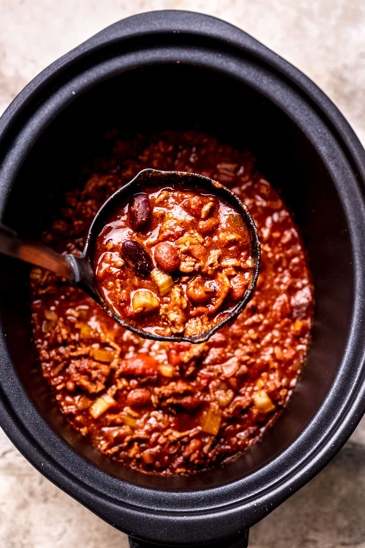 Slow cooker chilli con carne with a ladle.