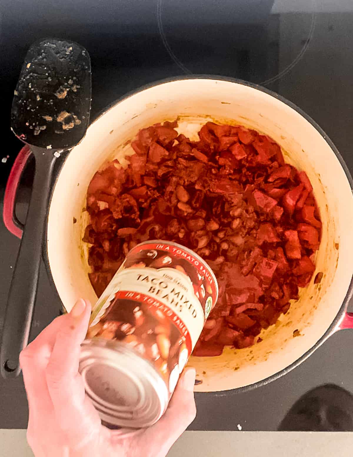Beans being added to a pot of chilli.