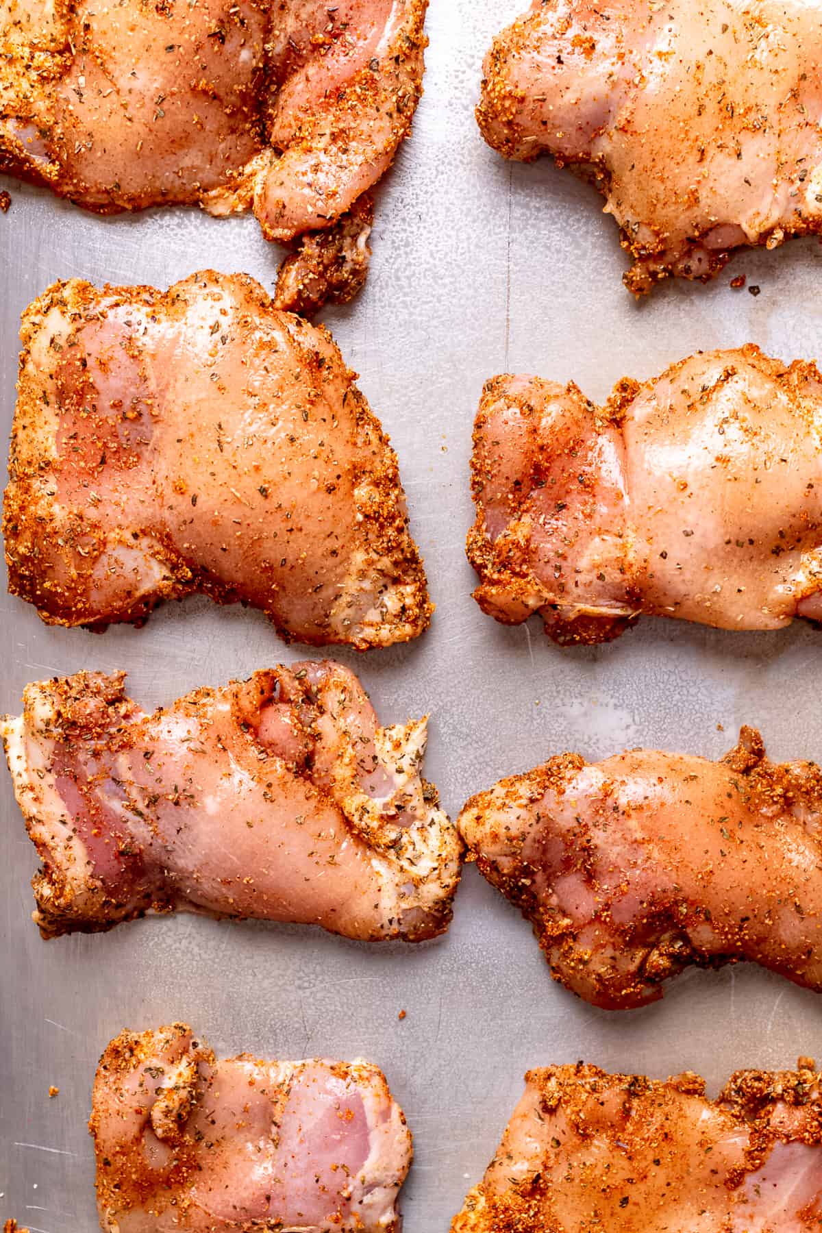 Spice-rubbed chicken thighs on a baking tray.