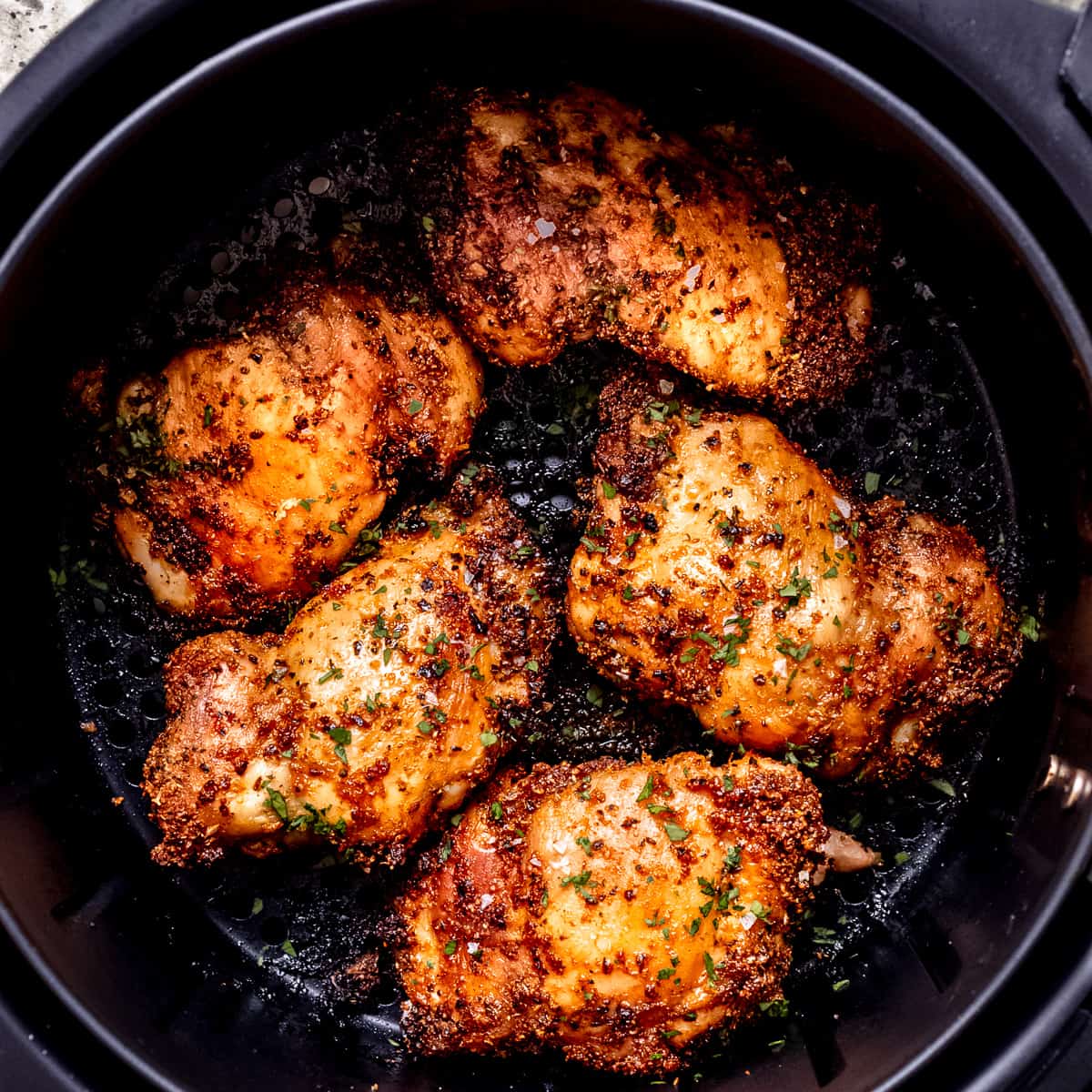 Air fryer chicken thighs in the fryer.