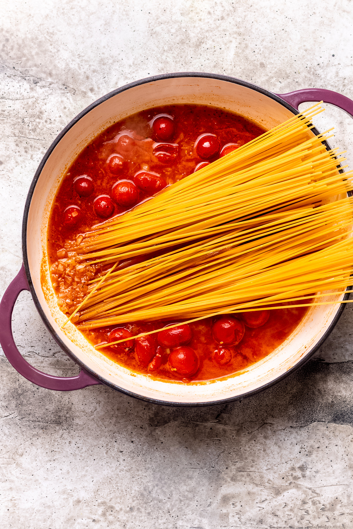 Pasta is added to tomato sauce to cook.