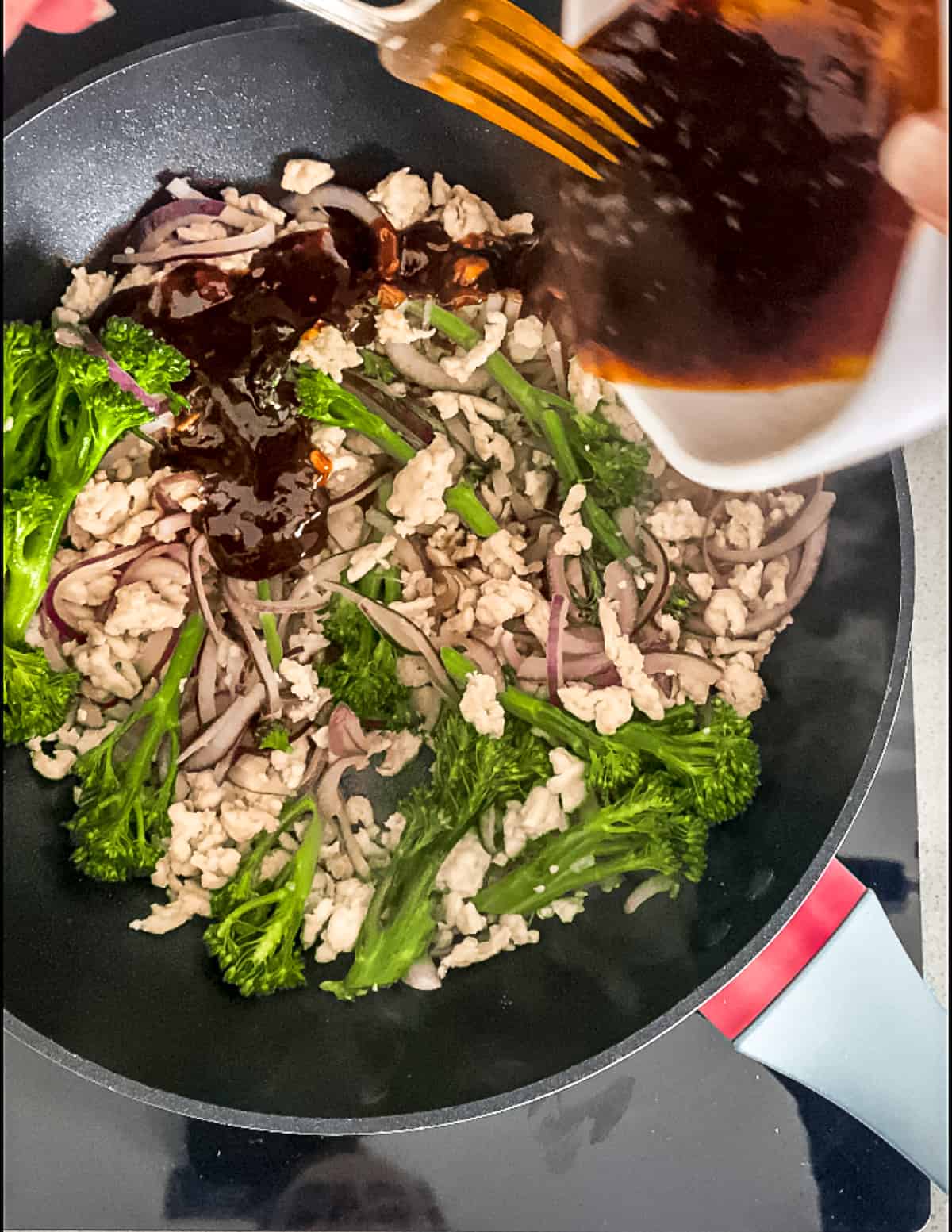 Sauce being added to turkey mince in a wok.