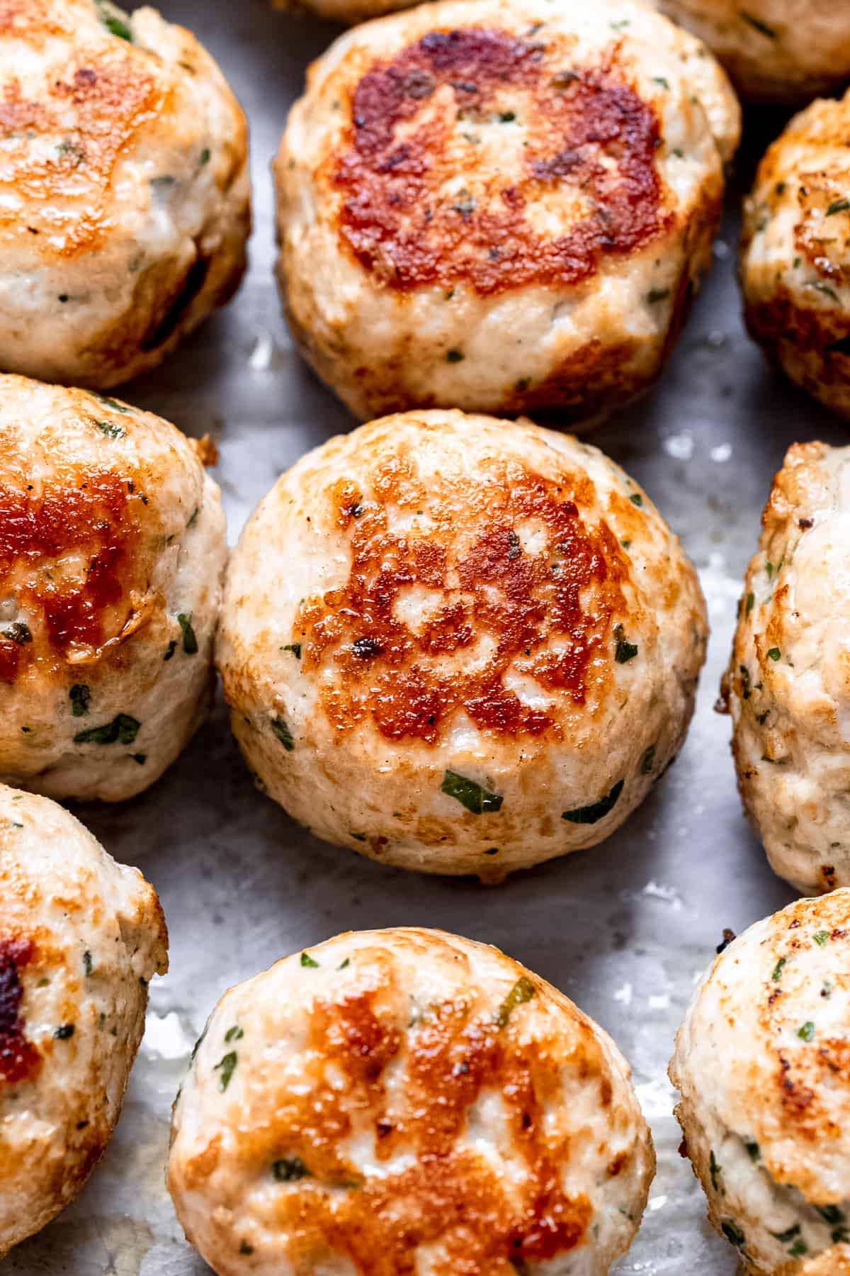 Seared meatballs on a baking tray.