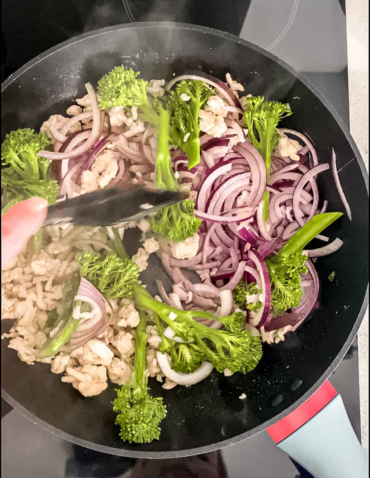 Vegetables being added to a wok with turkey.