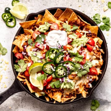 Loaded cheese nachos with chicken in a skillet.