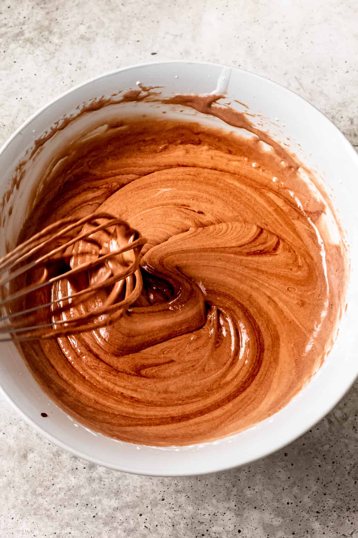 Whisking melted chocolate into brownie batter.