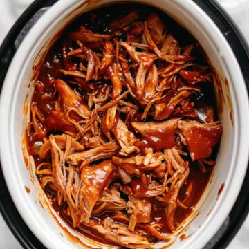 BBQ pulled chicken in a slow cooker with sauce.