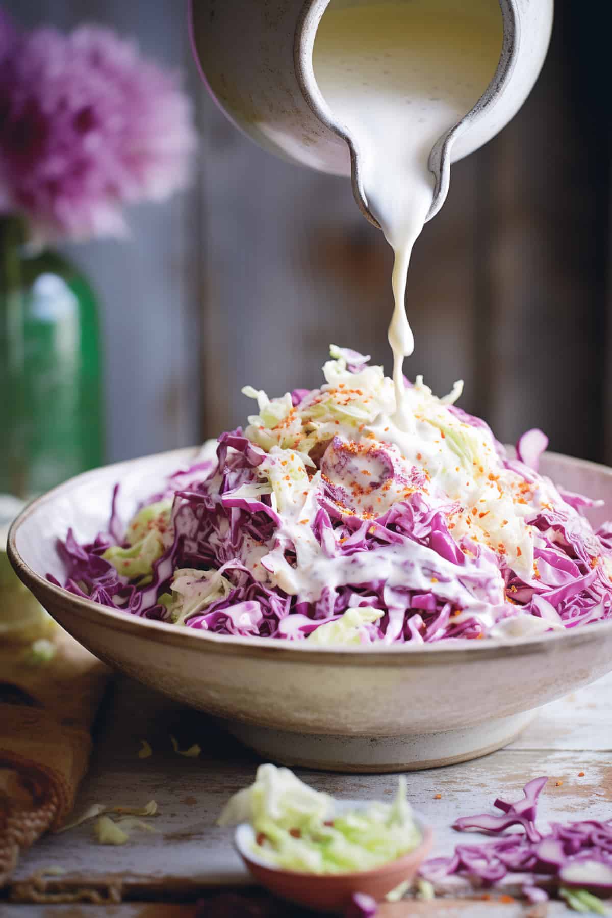 Coleslaw being drizzled with dressing.