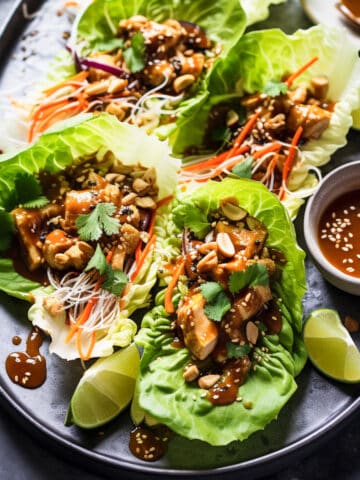 Asian chicken lettuce wraps with peanut sauce on a plate.