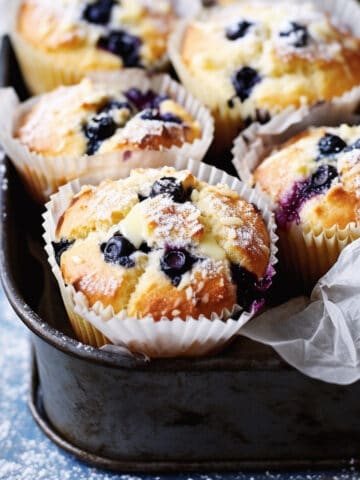 Fresh baked blueberry muffins in a baking tin.