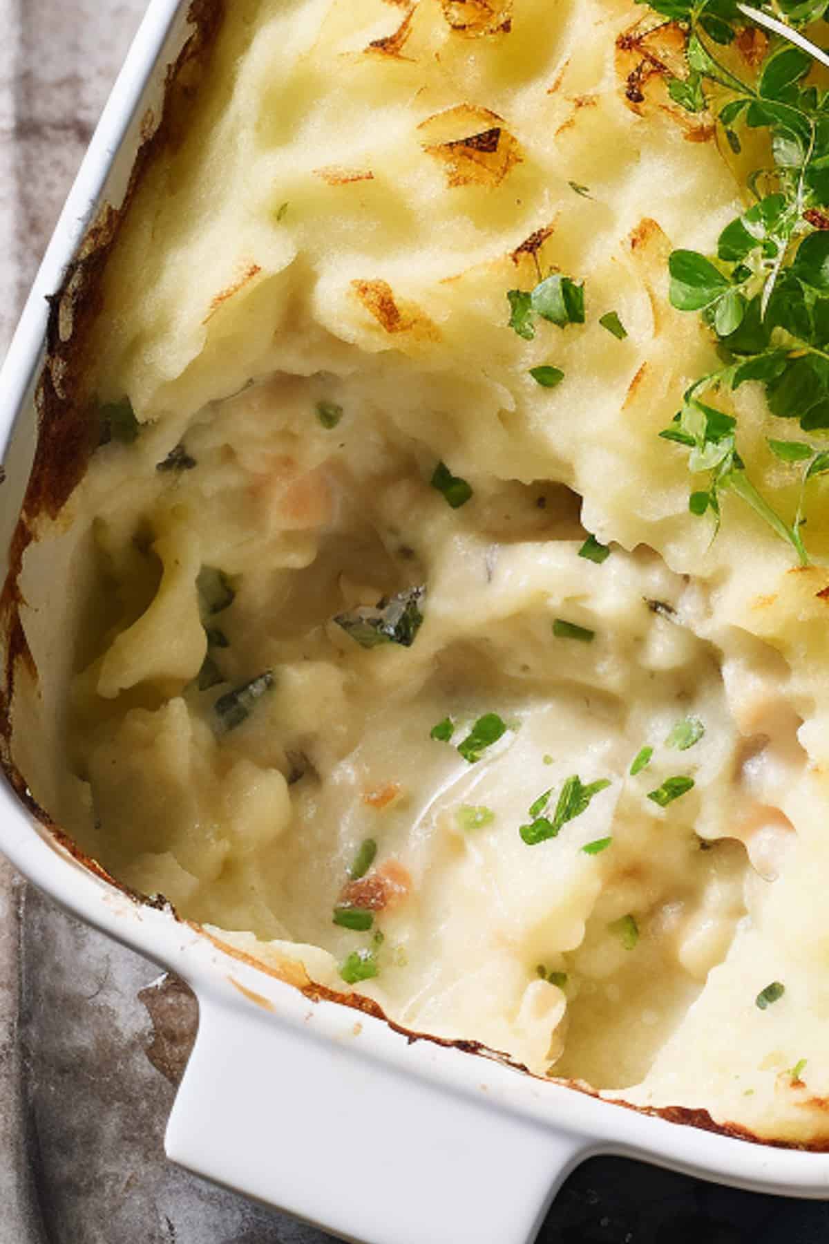 Close up of fish pie with chunks of seafood visible.