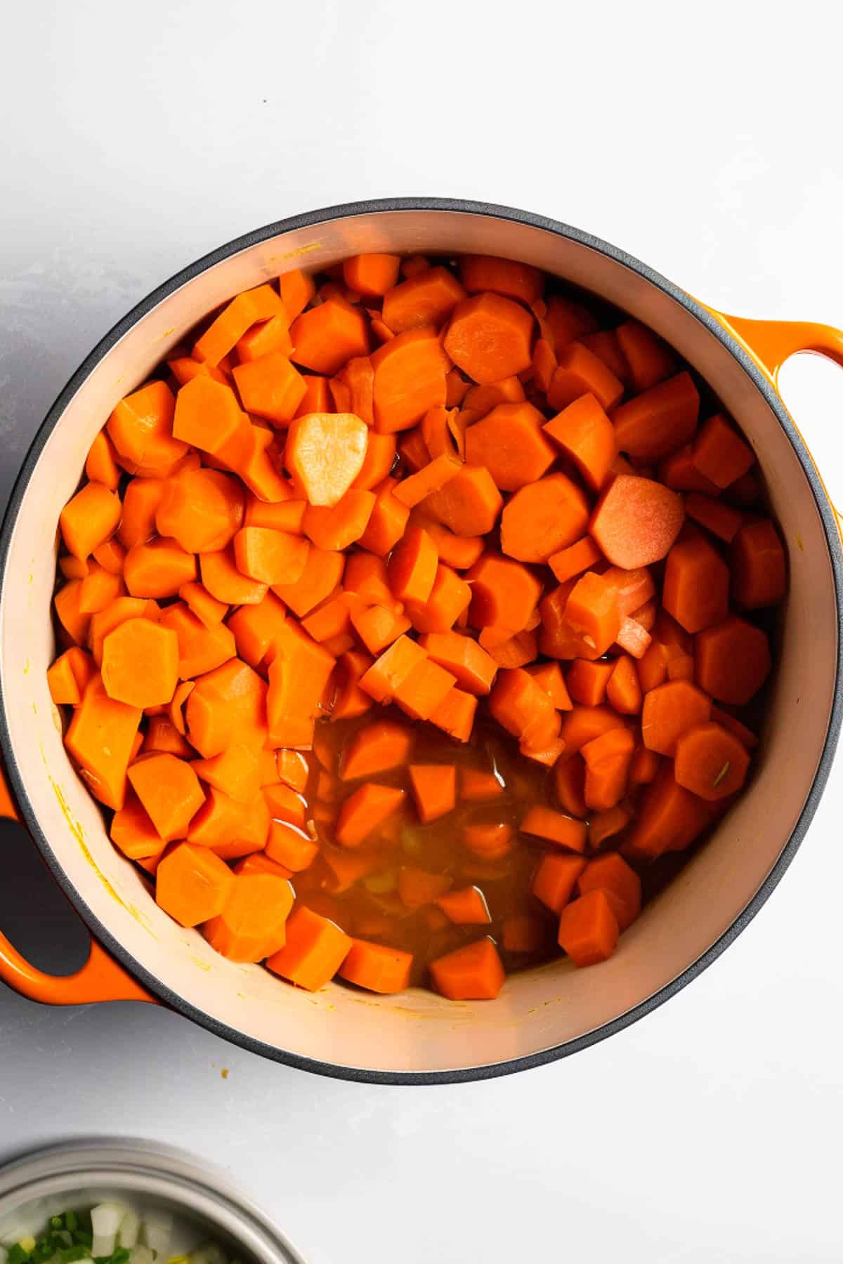 Chopped carrots in a pot with vegetable stock for carrot soup.