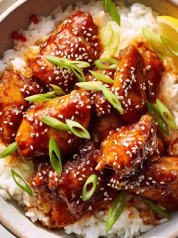 Korean chicken over rice in a white bowl.