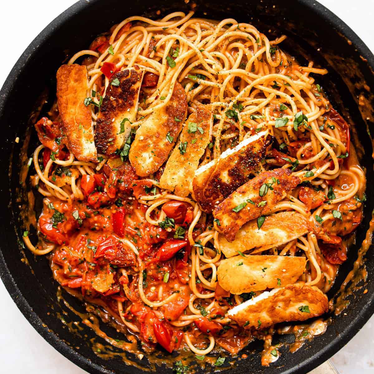 Halloumi pasta with tomatoes and spaghetti in a skillet.