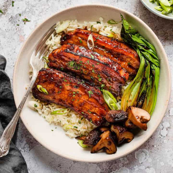 Roasted pork belly slices with honey garlic glaze on white rice.