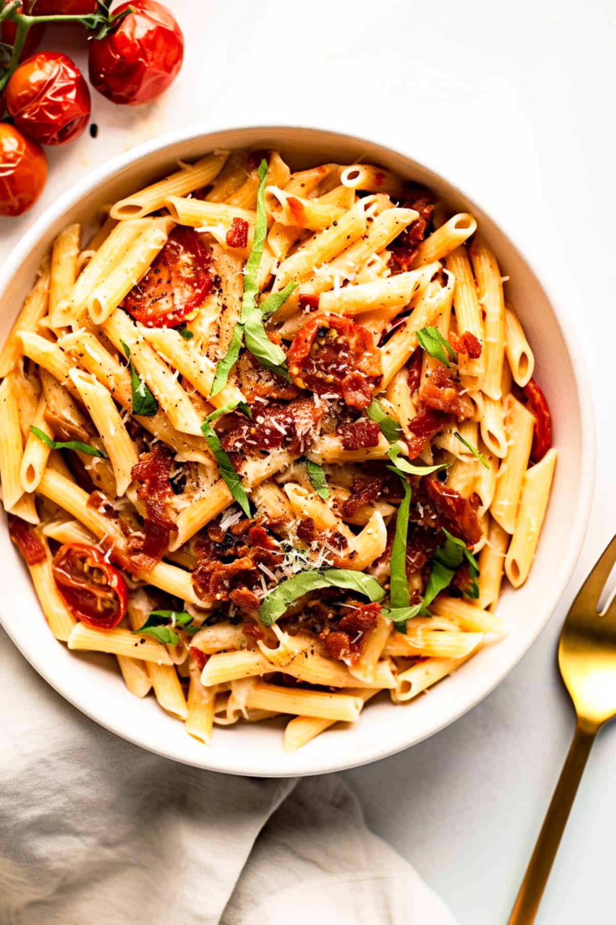 Sun-dried tomato pasta in a bowl with chopped basil and parmesan cheese.