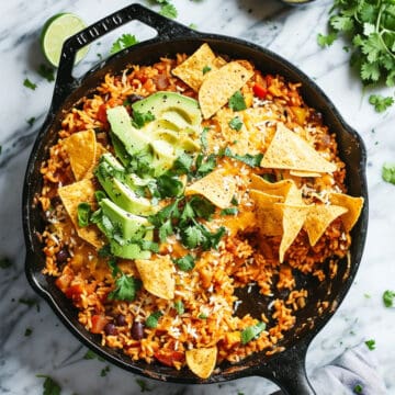 One pot Mexican rice in a skillet with avocado and tortilla chips.