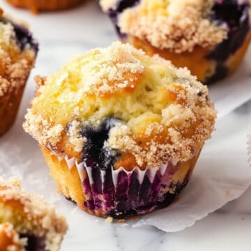 A batch of freshly baked blueberry muffins on a white table.