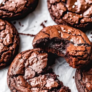A stack of chocolate biscuits sprinkled with sea salt on a white table.