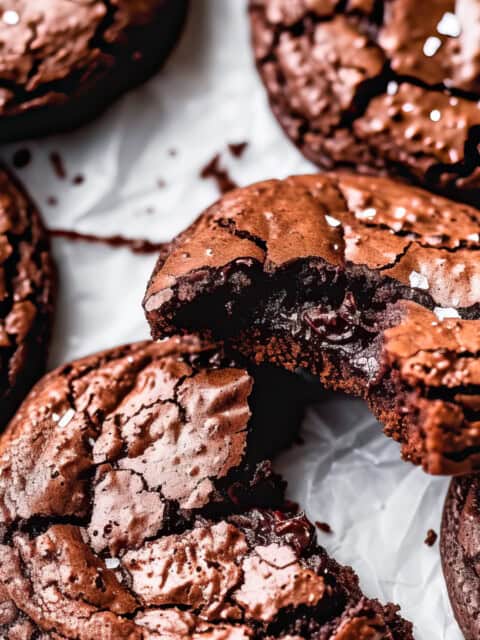 A stack of chocolate biscuits sprinkled with sea salt on a white table.
