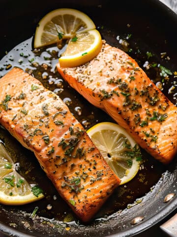 Pan-fried salmon with lemon and garlic in a skillet.