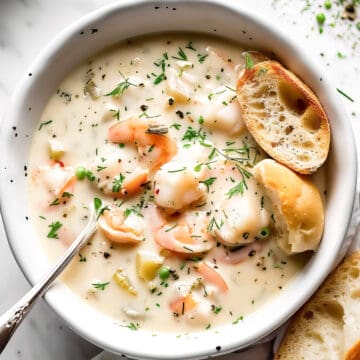 Creamy seafood chowder with salmon and prawns in a white bowl.