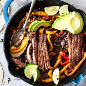 Steak fajitas with peppers and avocado in soft flour tortillas.