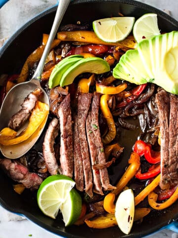 Steak fajitas with peppers and avocado in soft flour tortillas.