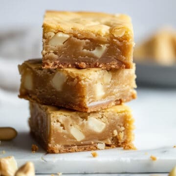 A stack of white chocolate blondies on a marble cutting board.