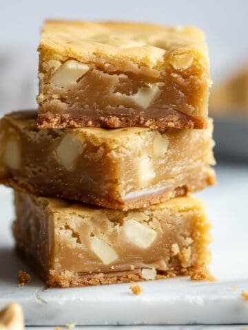 A stack of white chocolate blondies on a marble cutting board.