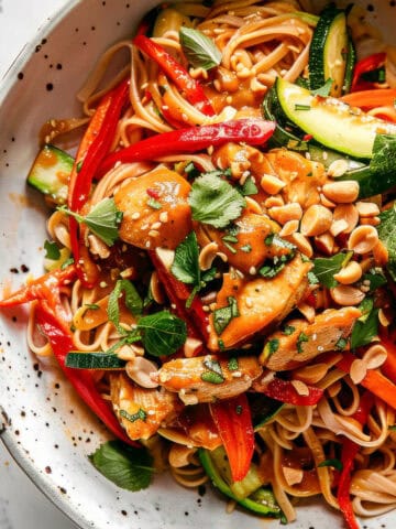 Easy bang bang noodles with chicken and peanuts in a white bowl.