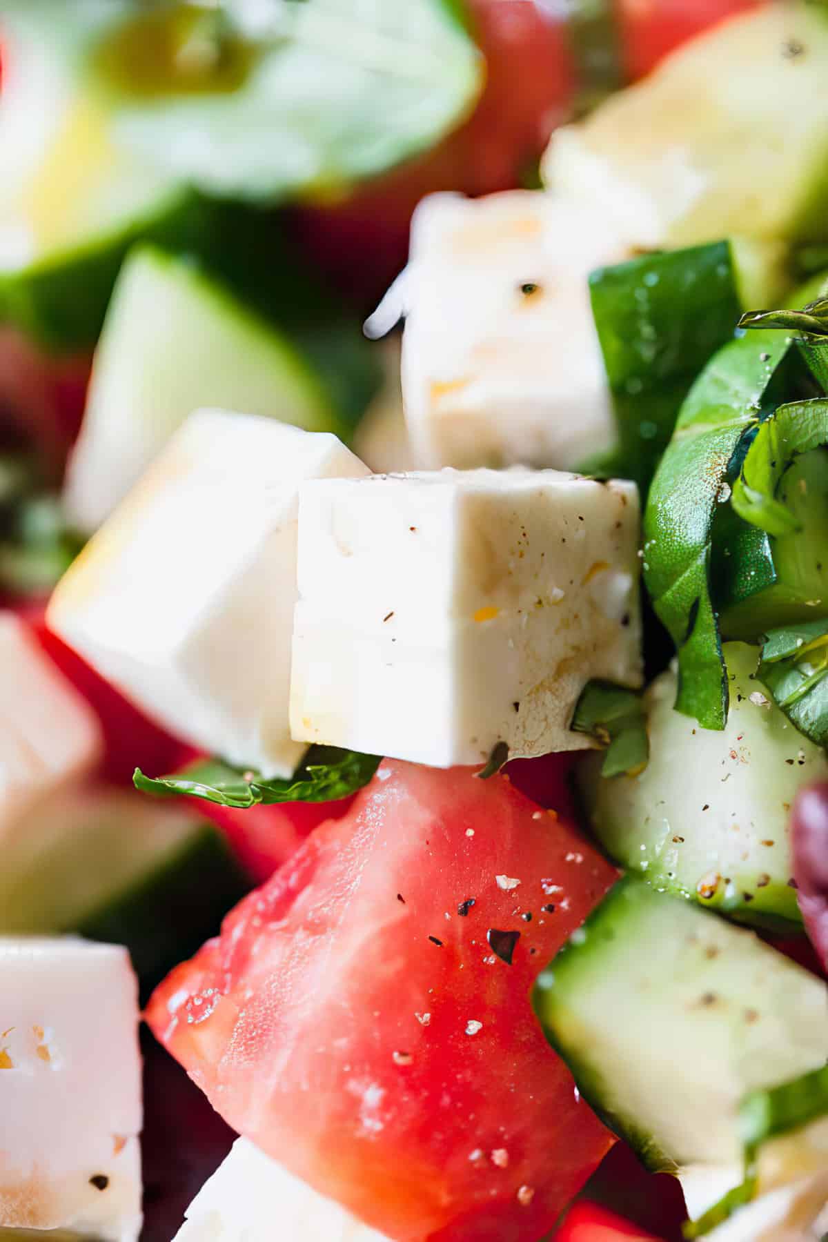 Close-up of watermelon and feta salad in a bowl with basil dressing.