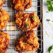 Crispy buttermilk chicken on a cooling rack with sea salt and thyme leaves.