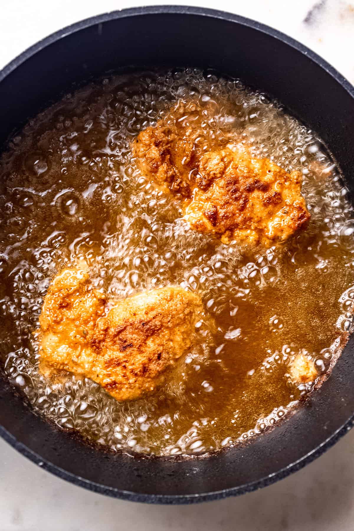 Chicken frying in a pan of oil.