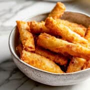 Crispy fried homemade egg rolls in a white bowl.