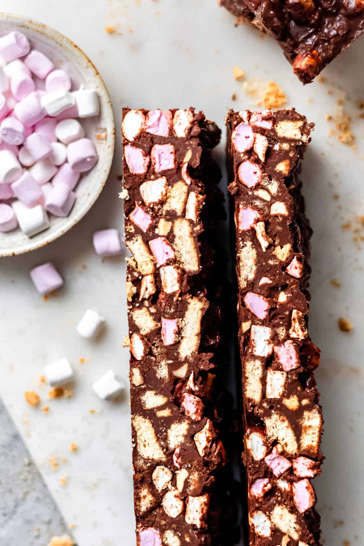 Rocky road bars on a white marble table with marshmallows.