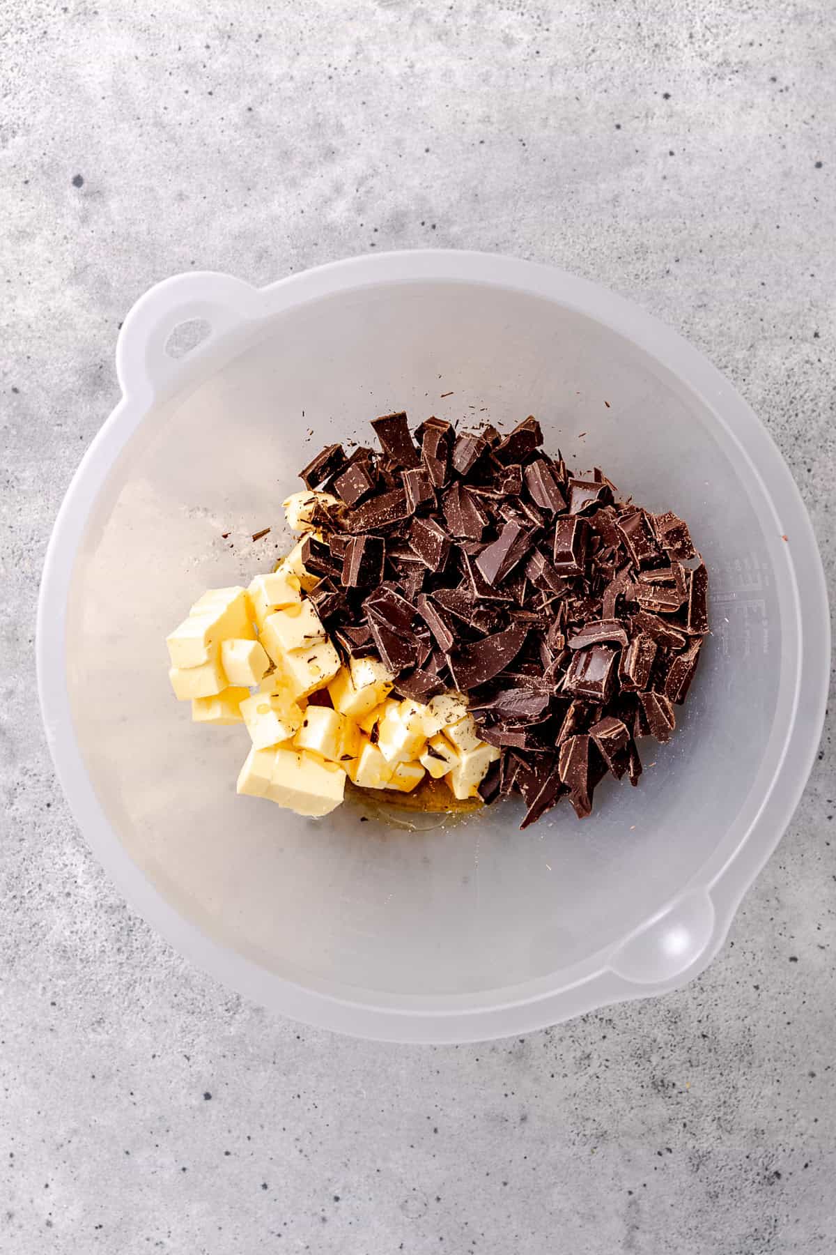 Chopped chocolate and butter with syrup in a bowl.