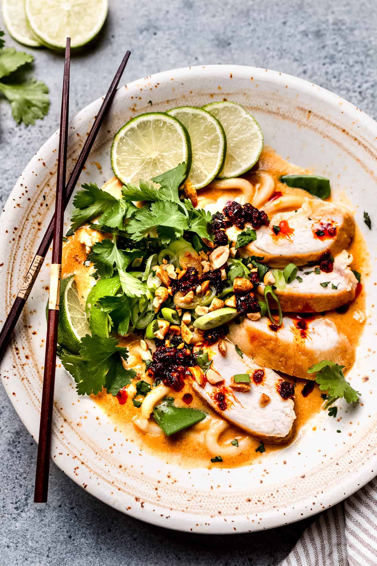 Spicy peanut ramen in a white bowl with chopped herbs.