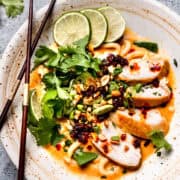 Spicy peanut ramen in a white bowl with chopped herbs.