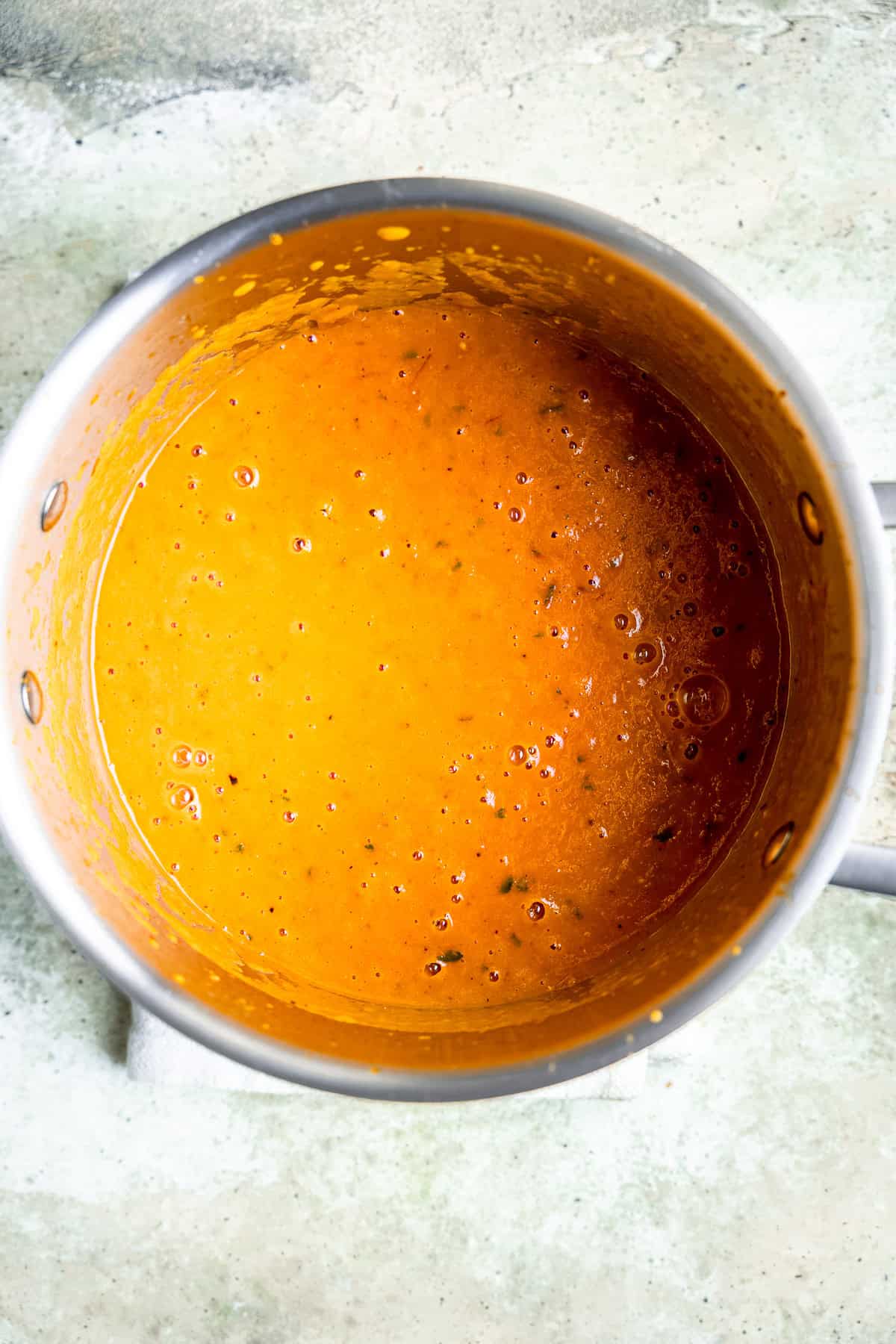 Roasted tomato soup being blended in a soup pot.