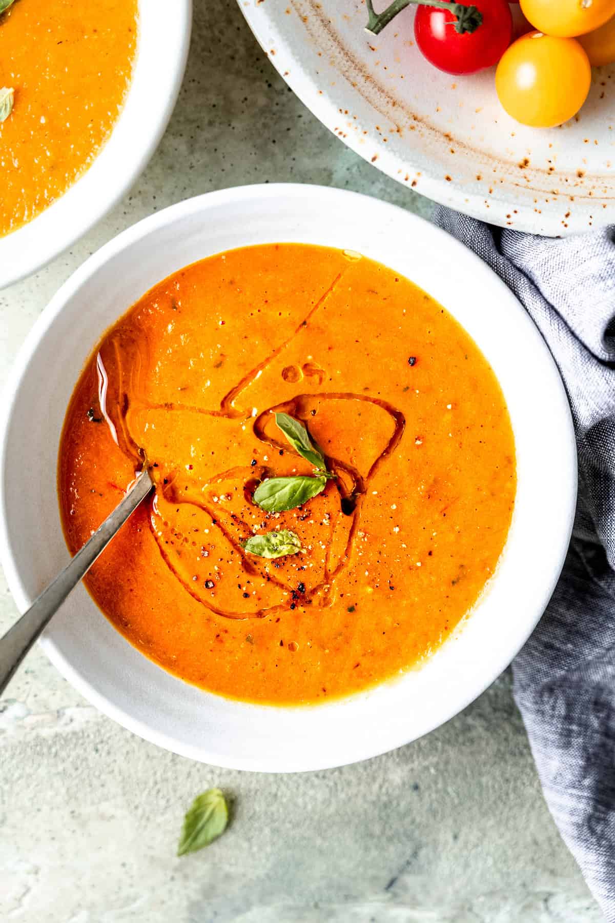 Roasted tomato soup with basil and olive oil in a bowl.