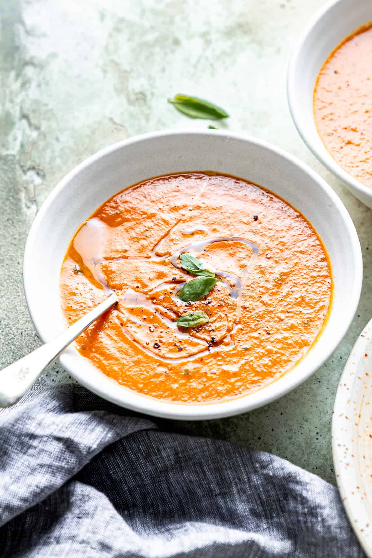 Roasted tomato soup with basil and olive oil in a bowl.