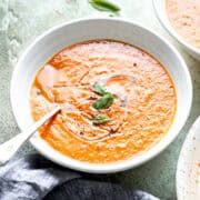 Roasted tomato soup with basil and olive oil in a bowl.