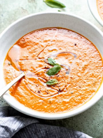 Roasted tomato soup with basil and olive oil in a bowl.