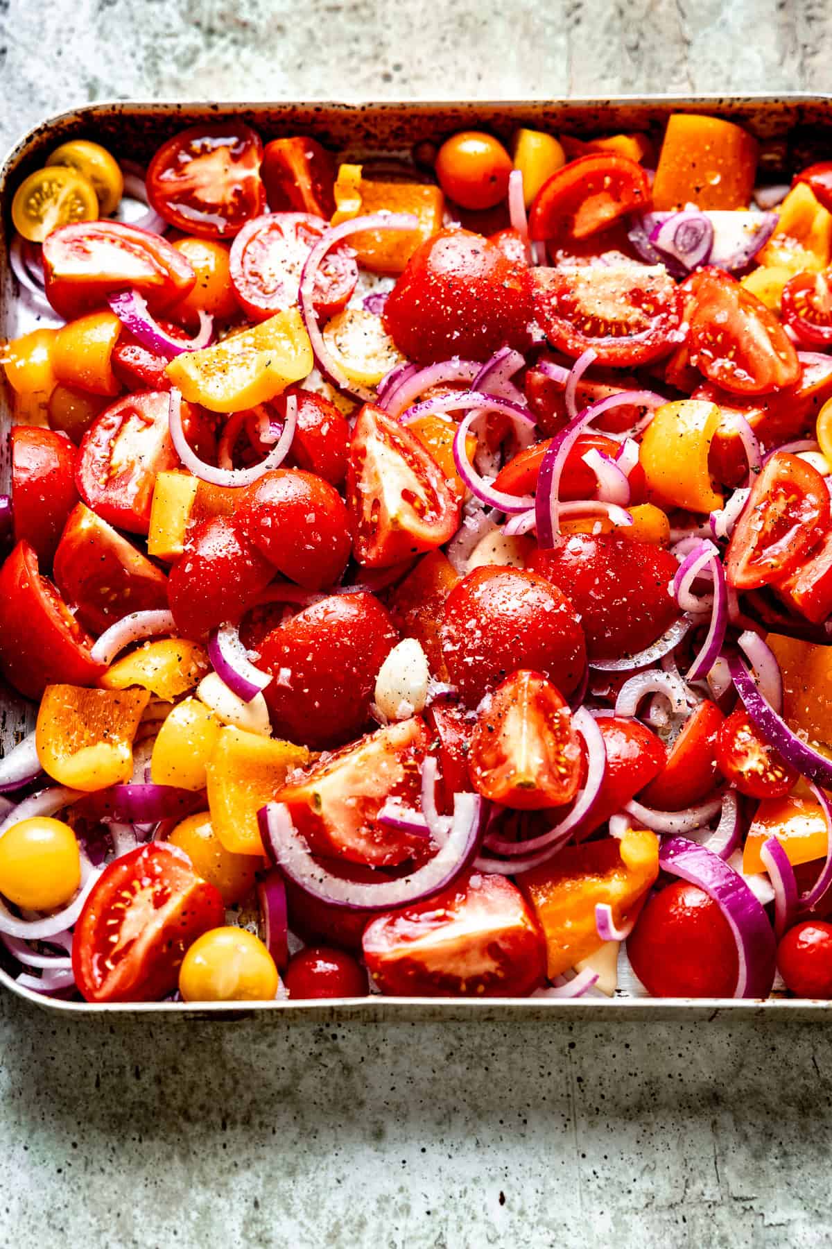 Fresh tomatoes in with garlic in a roasting pan for soup.