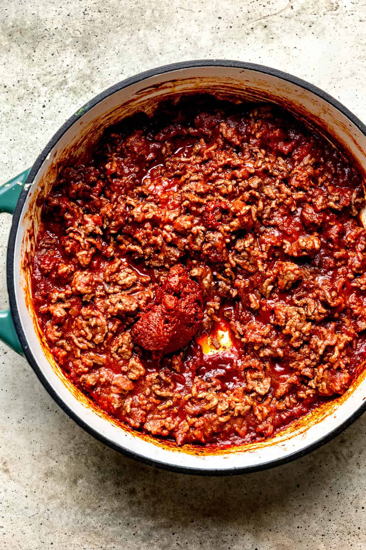 Tomato purėe paste being added to chopped tomatoes for pasta sauce with shells.