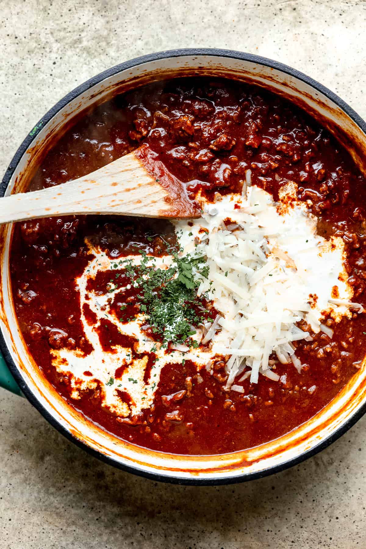 Cream and parmesan cheese being added to the bolognese sauce.