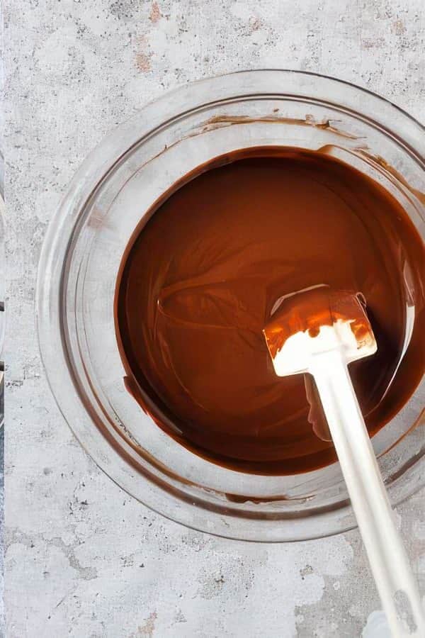 Melted chocolate and whisked eggs in bowls with a mixer.